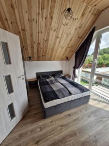 a bedroom with a bed and a wooden ceiling at Sosnowa Polana Rusinowo in Rusinowo