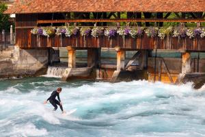 ein Mann, der auf einem Surfbrett im Wasser eine Welle reitet in der Unterkunft The Lab Hotel & Apartments in Thun