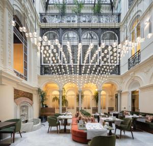 a restaurant with a large chandelier and tables and chairs at Palacio Gran Vía, a Royal Hideaway Hotel in Granada