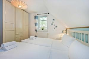 a white bedroom with two beds and a window at Loddin Ferienwohnung Inselzeit in Loddin