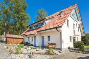 a white house with a red roof at Loddin Ferienwohnung Inselzeit in Loddin
