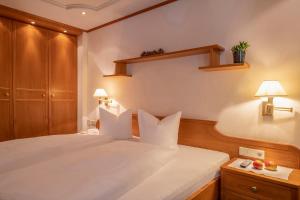 a bedroom with a large white bed with two lamps at Geniesserhotel Montafoner Hof in Tschagguns +85 photos