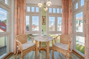 a dining room with a table and chairs and windows at Ferienwohnung Koralle in Koserow