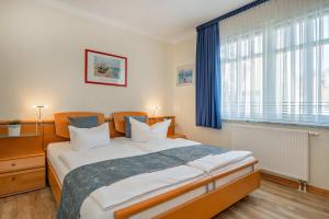 a bedroom with a large bed with blue curtains at Ferienwohnung Koralle in Koserow