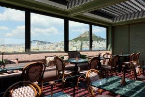 a restaurant with tables and chairs and a view of the city at Astor Hotel Athens in Athens