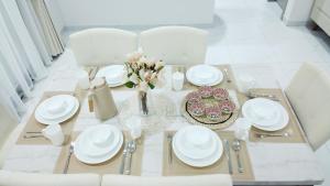 a dining table with white dishes and a vase of flowers at Rima Salalah in Salalah