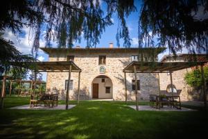 a stone building with tables and chairs in the grass at Agriturismo Castello Di Querceto in Lucolena in Chianti