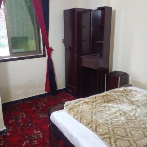 a bedroom with a bed and a cabinet and a window at UK Residencia in Murree