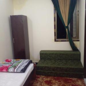 a bedroom with a green couch and a window at UK Residencia in Murree