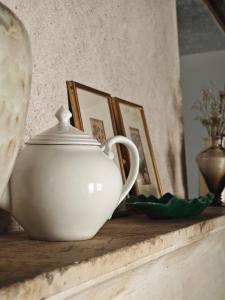 a white tea pot sitting on a table with pictures at Domaine du Moulin Français in Champougny