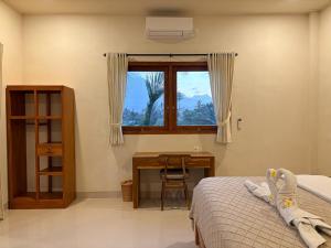 a bedroom with a bed and a desk and a window at Kayana Amed in Amed