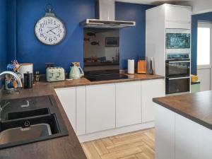 a kitchen with white cabinets and a clock on the wall at Alscott Cottage in Bishops Tawton