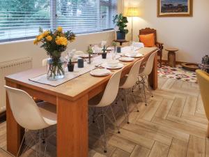 a long wooden table with chairs and a vase of flowers at Alscott Cottage in Bishops Tawton