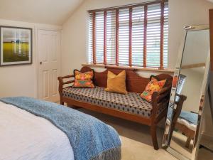 a bedroom with a bench with pillows and a window at Alscott Cottage in Bishops Tawton +13 photos