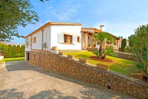 a white house with a stone retaining wall at Villa Can Tomas in Port de Pollensa