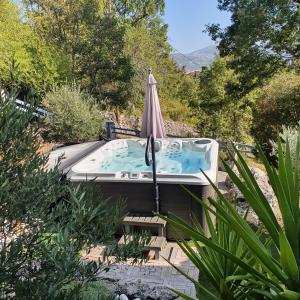 a hot tub in a garden with an umbrella at Villa Regain Chambres et table d'hôtes in Gréolières