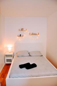 a white bedroom with a bed with a black object on it at Dormir près de Brioude - studio 'esprit vacances' in Fontannes