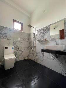 a bathroom with a sink and a toilet and a mirror at Rest Inn Tourist Hotel in Gampaha