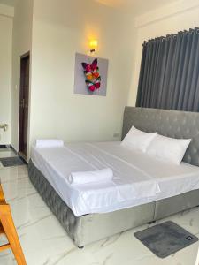 a bedroom with a large bed with white sheets at Rest Inn Tourist Hotel in Gampaha