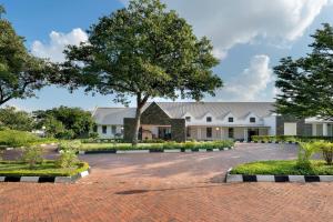 a large white building with a tree in the courtyard at Protea Hotel by Marriott Chingola in Chingola