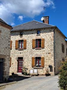 a brick building with brown shutters and a red door at La Parenthese in Folles
