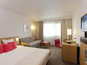 a hotel room with a bed and a couch at Novotel Pau Pyrénées in Lescar
