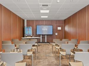 a conference room with a screen and tables and chairs at Novotel Pau Pyrénées in Lescar +112 photos