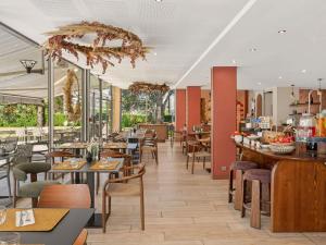 a restaurant with wooden tables and chairs and a cafeteria at Novotel Pau Pyrénées in Lescar