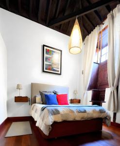 a bedroom with a bed with blue and red pillows at Casa Tradicional Canaria in Garachico