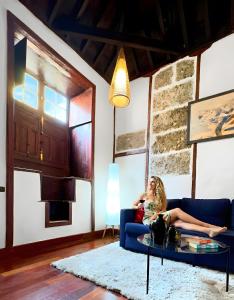 a woman sitting on a blue couch in a living room at Casa Tradicional Canaria in Garachico