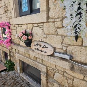 a sign on the side of a brick wall with flowers at Afet inn in Çeşme