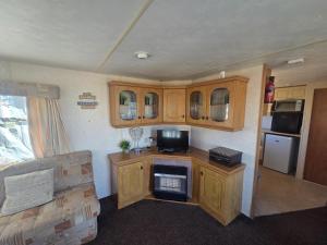an rv kitchen with wooden cabinets and a stove at Beckys Holiday Van in Ingoldmells +17 photos
