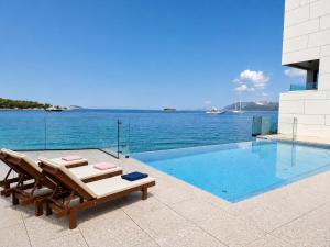 ein Schwimmbecken mit zwei Liegen neben dem Wasser in der Unterkunft Hotel Vallum by St Pietro in Cavtat + 52 Fotos