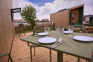 a green table with plates and glasses on a deck at Tiny House Nook 2 - Green&Tiny Hideaway Eider in Süderstapel