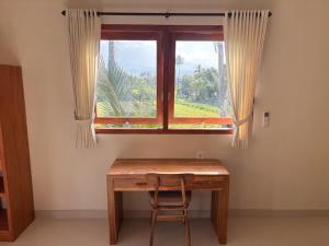 a wooden table with a chair in front of a window at Kayana Amed in Amed