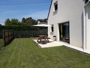 a patio with a picnic table and an umbrella at Maison La Plouhinecoise in Plouhinec