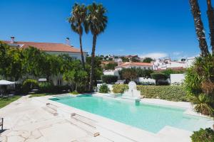 a swimming pool in a yard with palm trees at Pateo dos Solares Charm Hotel in Estremoz