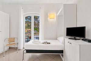 a white room with a bed and a television at Seaview Pool Retreat - Il Poggio in Marina di Andora