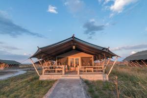 a building with a roof on top of a field at Mara Maisha Camp in Talek