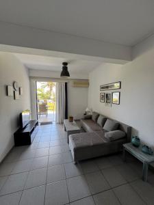 a living room with a couch and a table at Kinetious Nisous Stylish Apt, Pool, near the Beach in Kineta