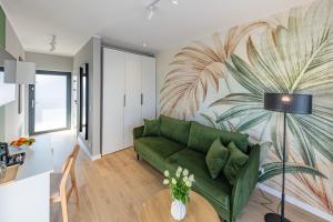 a living room with a green couch and a palm mural at Apartamenty i pokoje deluxe PÓŁNOCNA PRZYSTAŃ in Przewłoka