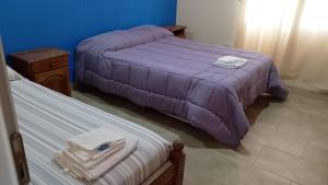 two beds in a bedroom with purple sheets and towels at El Boulevard in Viedma