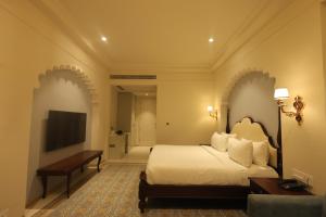 a bedroom with a bed and a desk and a television at Rajwada Hotel and Resort in Bareilly