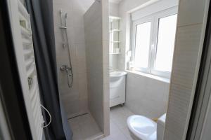a white bathroom with a shower and a toilet at Bonaca Room in Donja Lastva +5 photos
