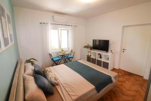 a bedroom with a bed and a couch and a television at Bonaca Room in Donja Lastva