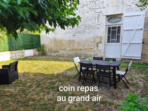 a table and chairs in a yard with the words coil reps au grand air at Gitevdelacour in Sainte-Même