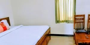 a bedroom with a bed and a table and a window at Goldan inn yercaud in Yercaud
