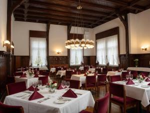 a dining room with white tables and chairs and a chandelier at Hotel Hermannshöhle in Elbingerode