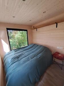 ein Bett in einem kleinen Zimmer mit Fenster in der Unterkunft Tiny House in Weismes