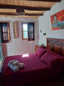 a bedroom with a large bed with purple sheets at Karallantay in Tilcara